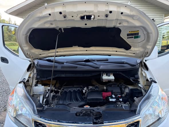 Open engine bay of a white Nissan van after detailing work